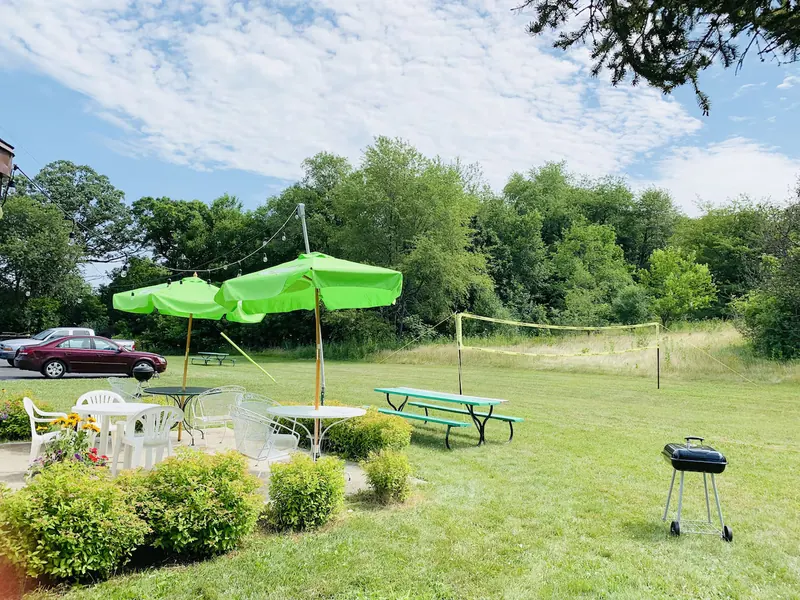 Lawn with garden umbrellas, a grill and a volleyball net